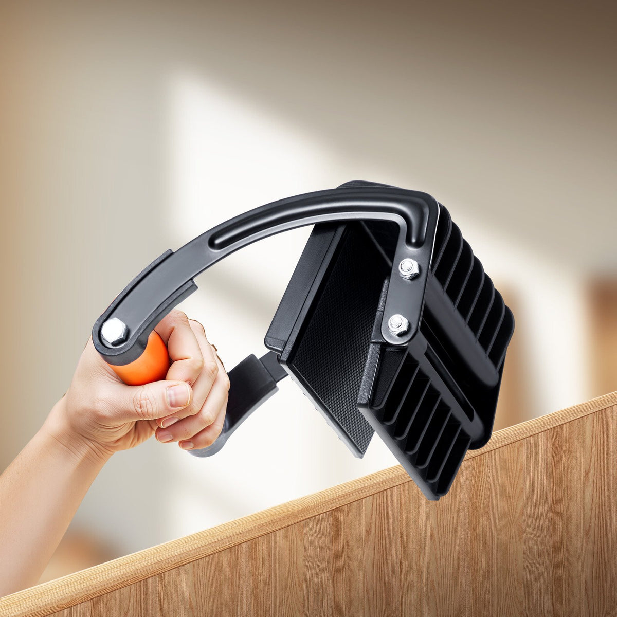Hand gripping the panel carrier as it clamps onto the top edge of a sheet